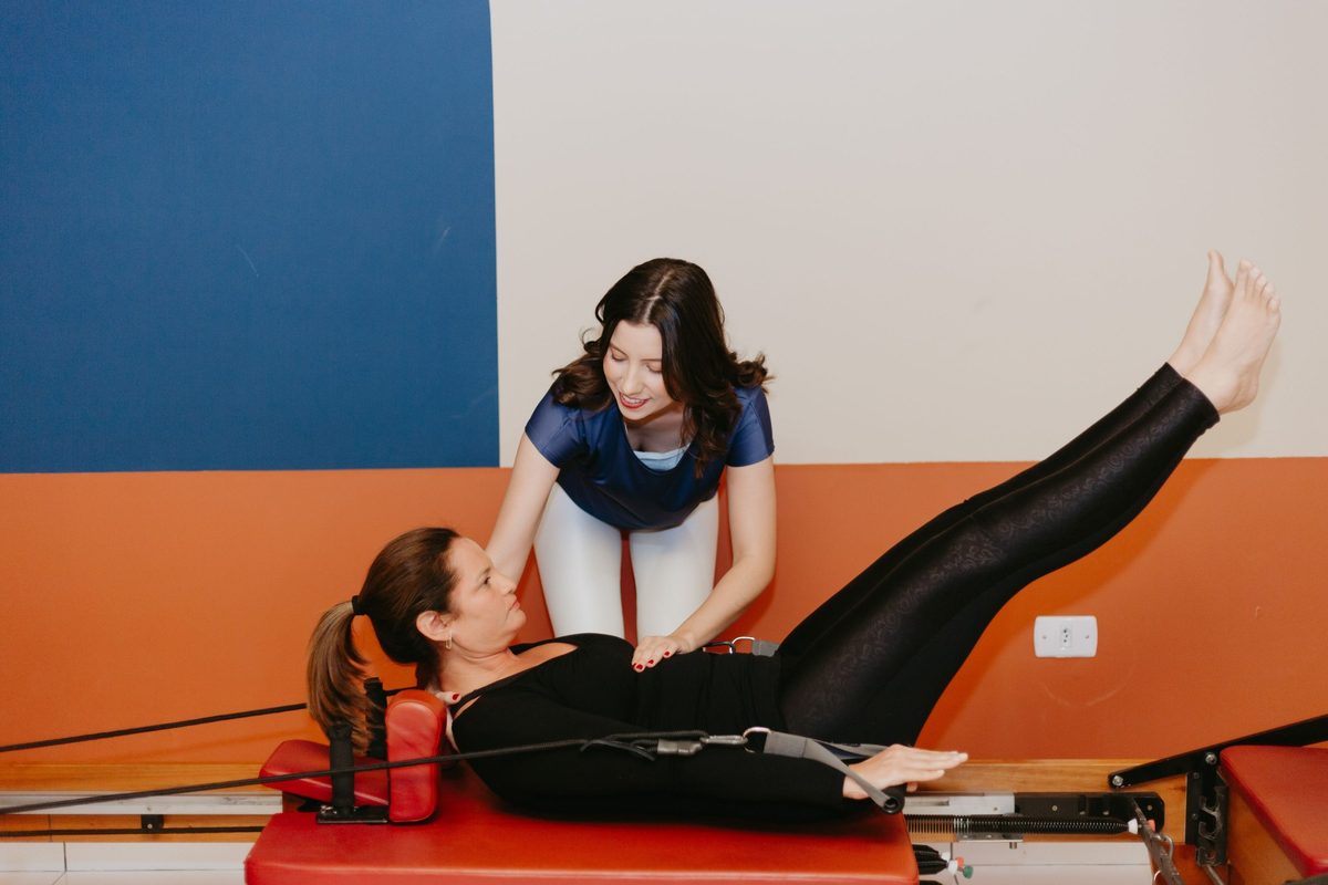 Fisioterapeuta orientando aluna no aparelho Reformer durante a Vivência de Pilates Clássico no estúdio Ella e Thau em Campo Grande-MS
